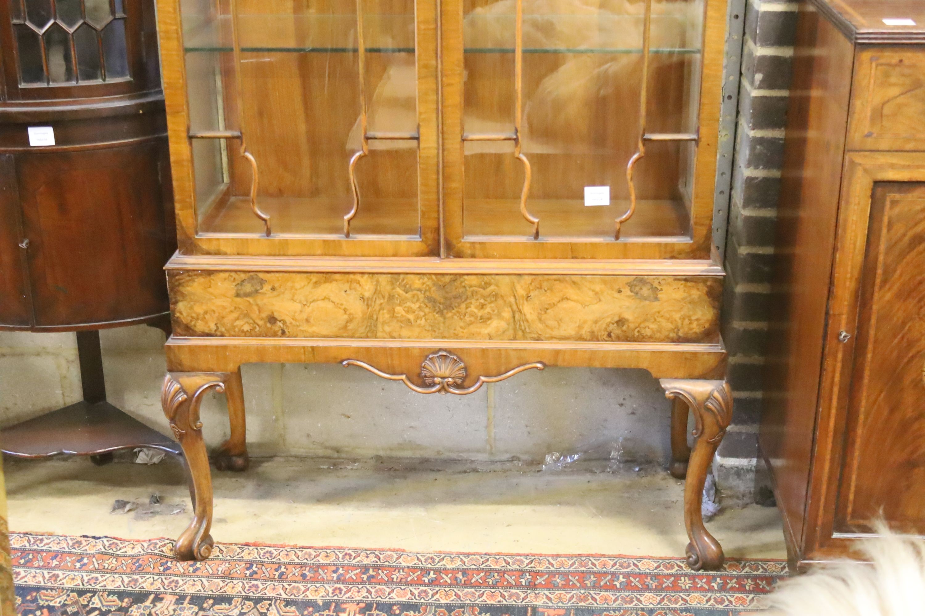 A George I style figured walnut display cabinet with glazed doors on cabriole supports and scrolled legs, width 100cm, depth 40cm, height 192cm
